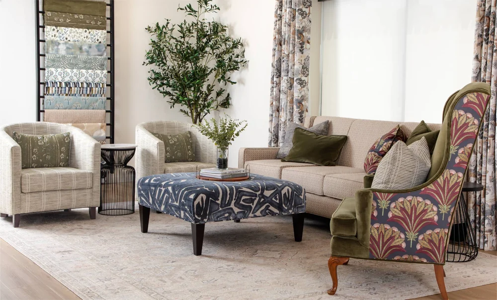 Styled 29 Park living-room vignette with upholstered chairs and sofa, patterned ottoman, pillows, drapery, and a wall display of fabric samples.