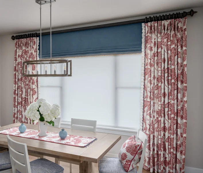 Floral drapery and a blue Roman shade in a Fabricut dining-room setting