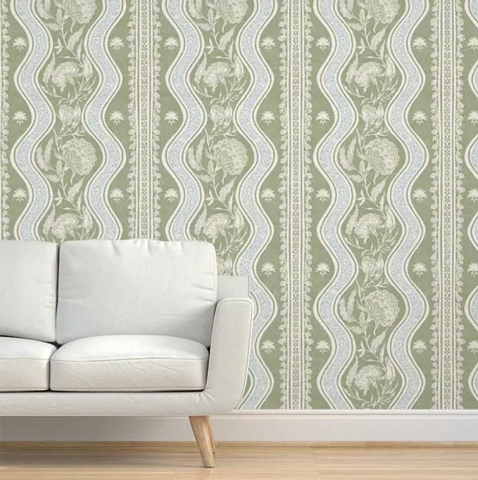 Sage-green ornamental wallpaper behind a light upholstered sofa on a wood floor